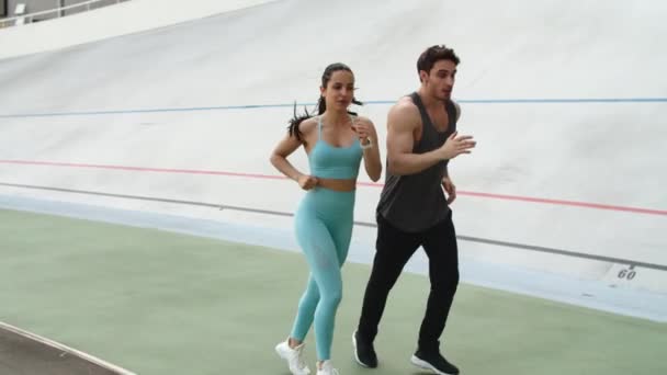 Entrenamiento de pareja de fitness juntos en el estadio moderno. Deportiva pareja corriendo — Vídeo de stock