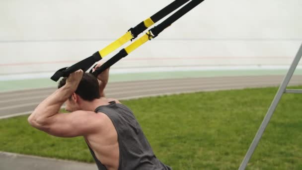 Фитнесмен, тренирующийся с трикс-подвеской на стадионе — стоковое видео