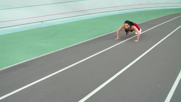 Chica deportiva haciendo ejercicio en ropa deportiva en el estadio deportivo. Sexy chica haciendo flexiones — Vídeos de Stock