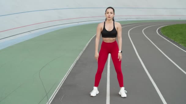 Mujer deportiva entrenando al aire libre en pista de atletismo. Mujer deportiva haciendo ejercicio — Vídeos de Stock