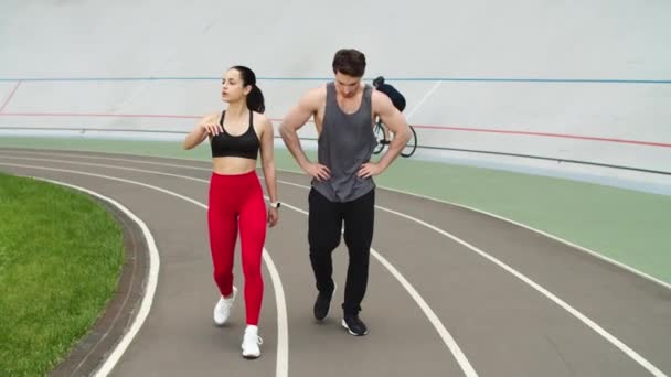 Casal exausto tendo pausa após o treinamento em conjunto na pista de atletismo — Vídeo de Stock