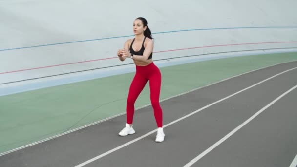 Fitness lány guggoló gyakorlatokat végez a versenypályán. Sportos nő gyakorlása — Stock videók