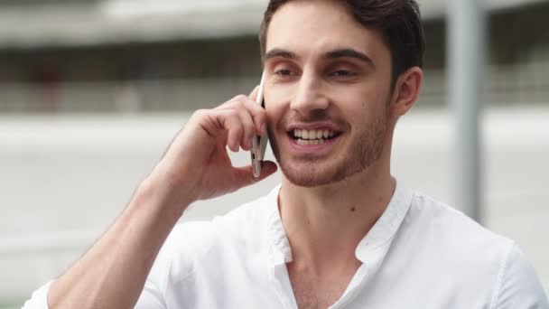 Porträt eines glücklichen Geschäftsmannes, der draußen mit dem Handy telefoniert — Stockvideo