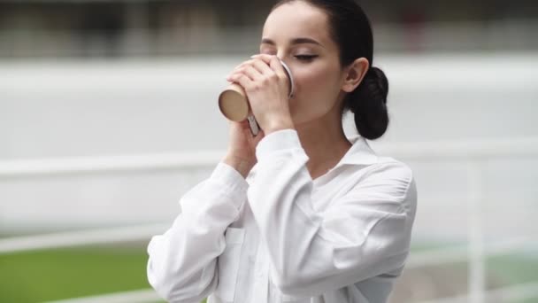 Een zakenvrouw die buiten telefoneert. Meisje drinken koffie op pauze buiten — Stockvideo