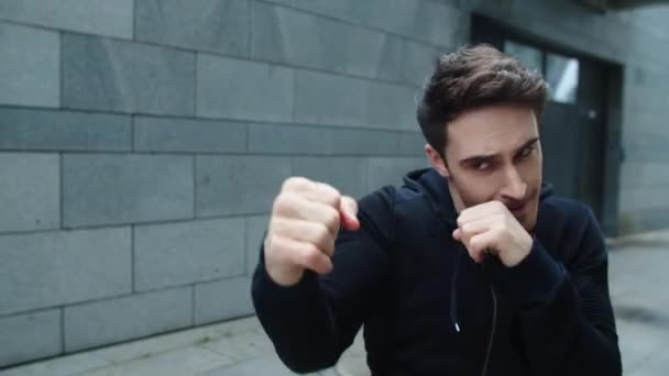 Koncentrált férfi boksz ütést edz a város utcáján. Fiatal férfi boksz szabadban — Stock videók