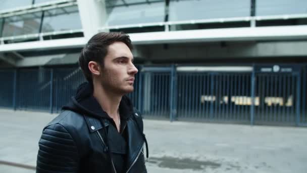 Рокер ходит по улице в черной куртке. Молодой человек, идущий в пустой город . — стоковое видео