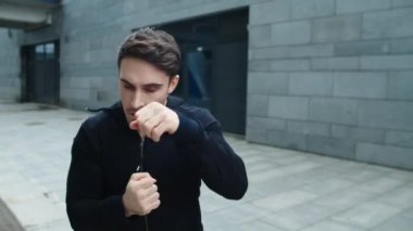 Genç adam dışarıda ağır çekimde yumruk eğitimi alıyor. Antrenmanda çalışan adam.