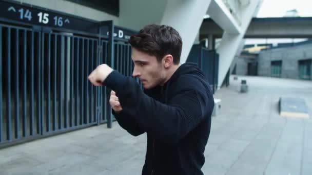 Молодой человек боксирует на городской улице. Портрет тренировочного удара кикбоксера — стоковое видео