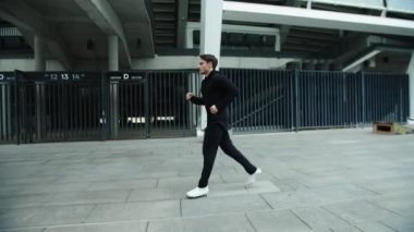 Şehir sokaklarında ağır çekimde koşan bir sporcu. Koşucu erkek dışarıda koşuyor.