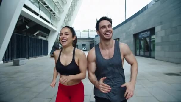 Feche o par alegre que corre ao ar livre. Rindo homem e mulher corrida de treinamento — Vídeo de Stock