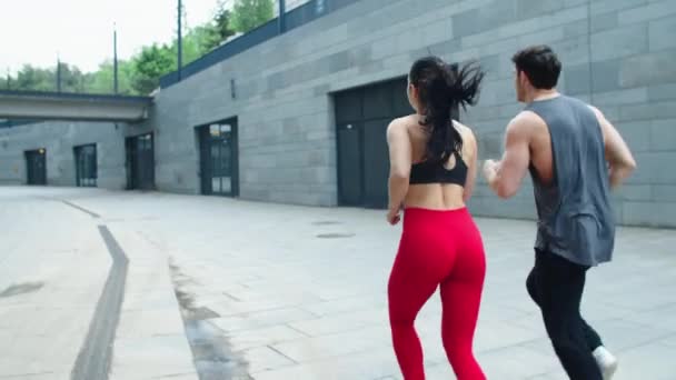 Back view of young couple running outdoor together. Sporty family training run. — Stock Video