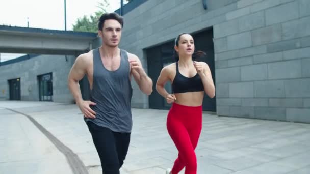 Fitness pár běží na městské ulici spolu. Sportovní rodinný trénink — Stock video