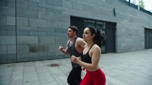 Sporty couple running outdoor together. Young man and woman training run outdoor — Stock Video