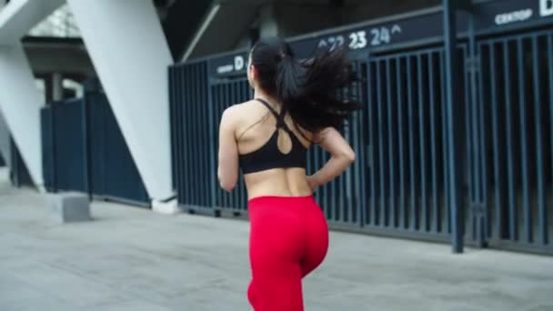 Вид сзади на здоровую женщину, бегущую на улице. Тренировки для девочек возле стадиона . — стоковое видео