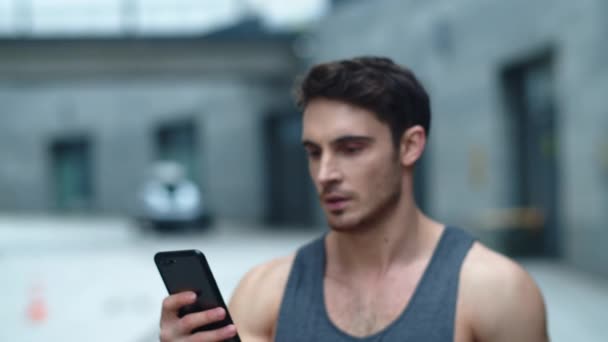 Primer plano atleta hombre mirando smartphone en la calle. Sonriente hombre leyendo el mensaje — Vídeos de Stock