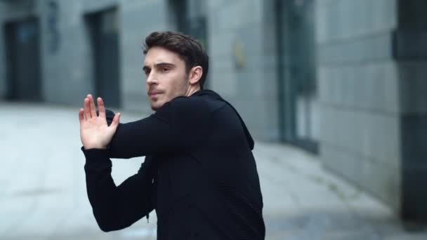 Handsome man stretching arms on workout outdoor. Male athlete warming up — Stock Video