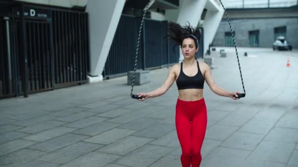 Atleta mujer saltando en saltar la cuerda al aire libre. Chica en forma haciendo ejercicio de salto — Vídeo de stock