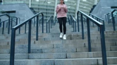 Spor salonundaki kadın merdivenlerden aşağı koşuyor. Sportif kız antrenmandan sonra dinleniyor.