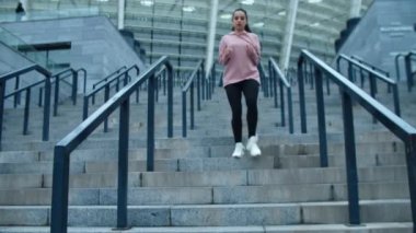 Merdivenlerden dışarı koşan sportif bir kadın. Koşucu kadın merdivenlerden aşağı koşuyor.