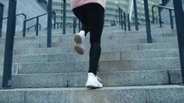 Kapalı kadın bacakları dışarıda merdivenlerden yukarı koşuyor. Fitness kızı üst kata çıkıyor..
