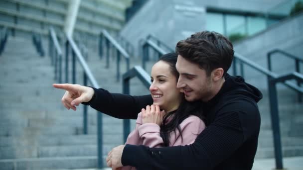 Retrato de pareja sonriente abrazándose al aire libre. Hombre alegre señalando de un lado a otro — Vídeos de Stock