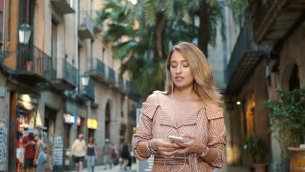 Mulher feliz usando fones de ouvido ao ar livre. Sorrindo menina ouvindo música na rua. — Vídeo de Stock