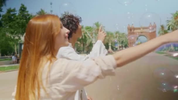 Casal feliz brincando com bolhas. Amigos sorridentes se divertindo com bolhas de sabão — Vídeo de Stock