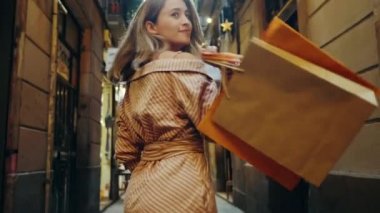 Alışveriş yapan kadının şehir caddesinde yürüyüşü. Kameraya bakan turist kız.
