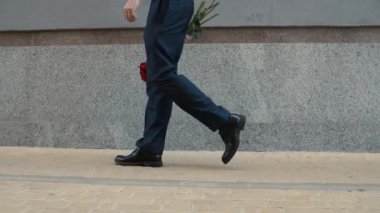 İş adamı dışarıda buluşuyor. Çiçek taşıyan bir adam