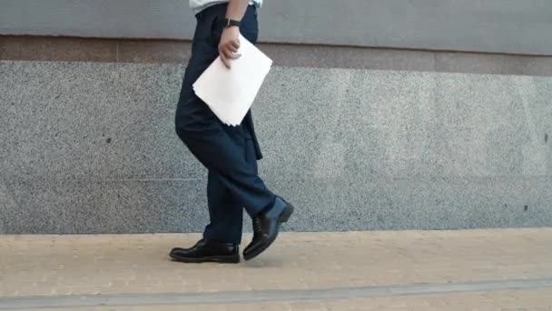 Крупный бизнесмен ходит с документами на улице. Человек держит бумаги на открытом воздухе — стоковое видео