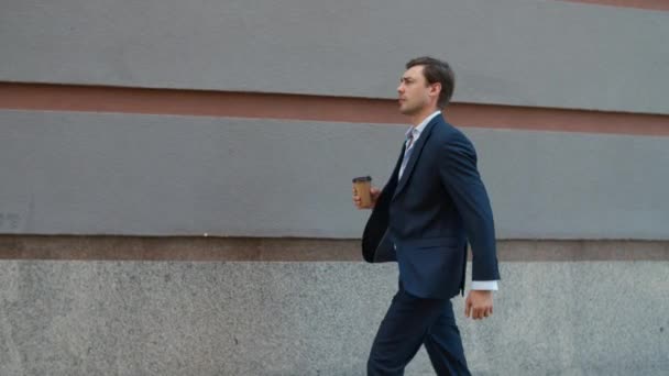 Un homme sérieux marchant avec du café dans la rue. Un homme va à une réunion avec un café — Video