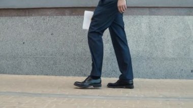 Kesilmiş resimli adam belgelerle yürüyor. Dışarıda ayakkabı giyen yakın plan bir adam.