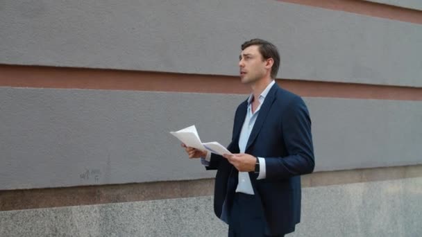 Um homem de negócios sério a ler documentos. Homem caminhando com documentos na rua — Vídeo de Stock