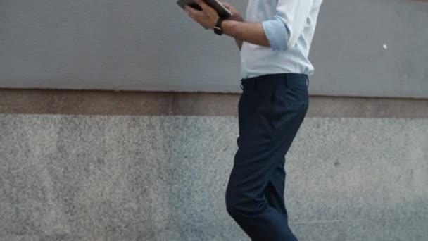 Primer hombre de negocios caminando con la tableta. Hombre recibiendo buenas noticias en la tableta al aire libre — Vídeos de Stock