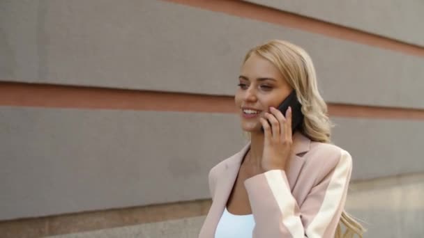 Женщина с крупным планом разговаривает по телефону на улице. Девушка идет в офис с телефоном — стоковое видео