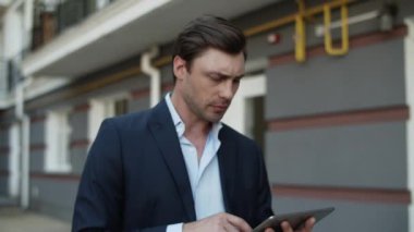 Sokakta tablet kullanan bir iş adamı. Dışarıda dokunmatik bir yerde çalışan bir adam var.