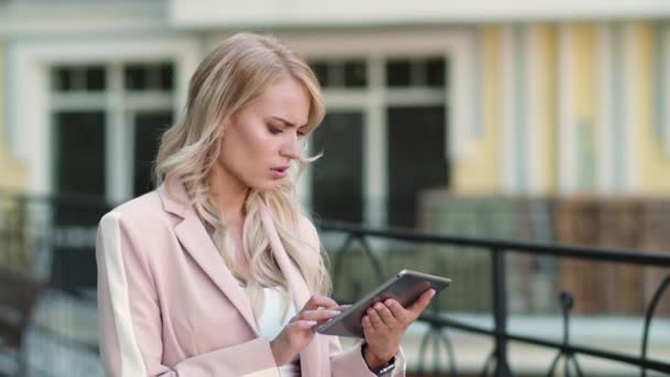 Una mujer de cerca recibiendo malas noticias en el panel táctil. Mujer trabajando en tablet en la calle — Vídeos de Stock