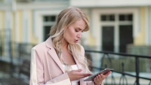 Donna in primo piano che lavora su touchpad in strada. Donna che utilizza tablet in abito rosa — Video Stock