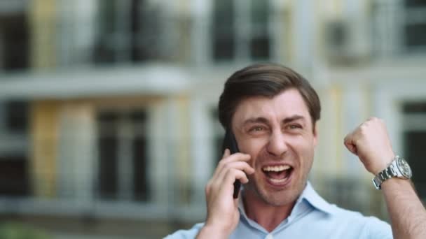 Un hombre de negocios de cerca celebrando la victoria. Hombre hablando por teléfono en la calle — Vídeos de Stock