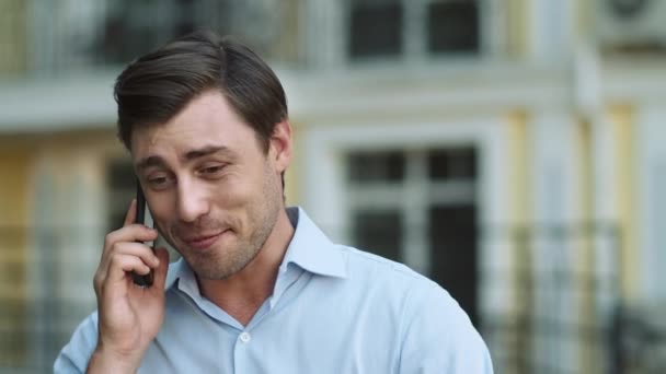 Портретист разговаривает по телефону на улице. Мужчина разговаривает по телефону в рубашке на открытом воздухе — стоковое видео