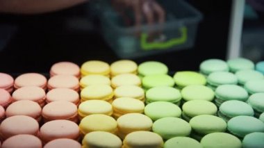 Kapanış şefi vitrine makarna koyuyor. Mağaza camında renkli kurabiyeler