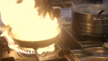 Erkek aşçı mutfak restoranında yemek pişiriyor. Ağır çekimde ateş.
