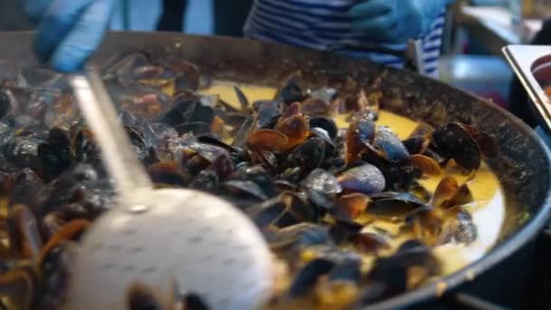 Gros plan moules juteuses cuisson dans wok. Gros plan chef main agitant mollusque frais — Video