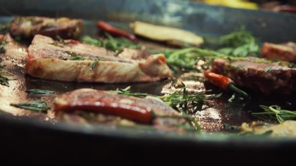 Gros plan de bœuf grillé avec des herbes sur la poêle. Friture de viande juteuse au ralenti — Video