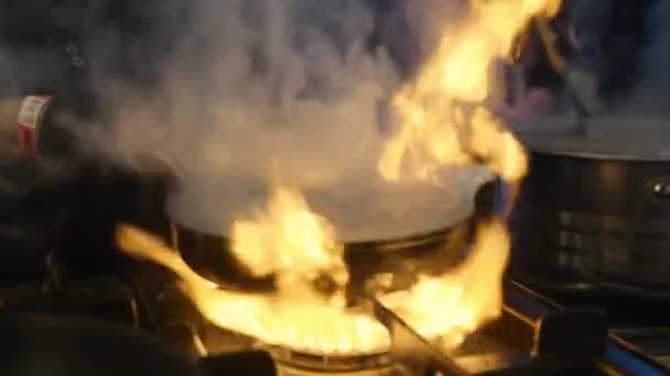 Primeros planos manos de chef masculino arrojando comida con pinzas. Cocinero freír verduras . — Vídeo de stock