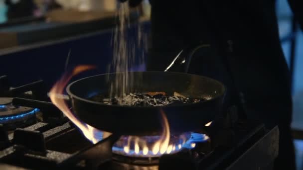 Närbild manliga kock händer förbereder mat i brand. Spis som tillsätter riven ost — Stockvideo