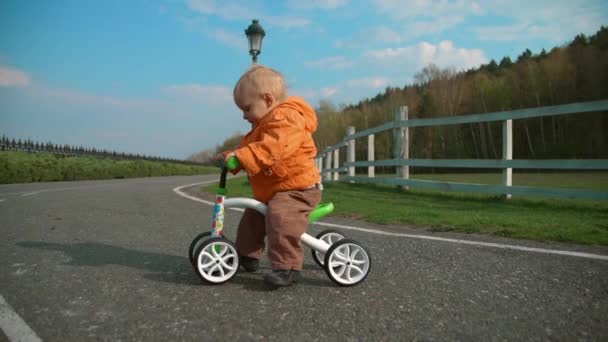 遅い動きで自転車で道路を横断する小さな子供。サイクルに乗って集中少年. — ストック動画