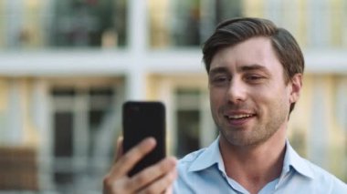 Portreci adam görüntülü konuşma için telefonu kullanıyor. İş adamı dışarıda video görüşmesi yapıyor.