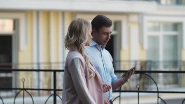 Tablet bilgisayar kullanan ciddi bir iş çifti. İş ortakları dışarıda konuşuyor.