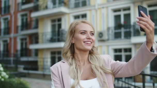 Portrait femme utilisant appel vidéo à l'extérieur. Femme d'affaires marchant en costume rose — Video